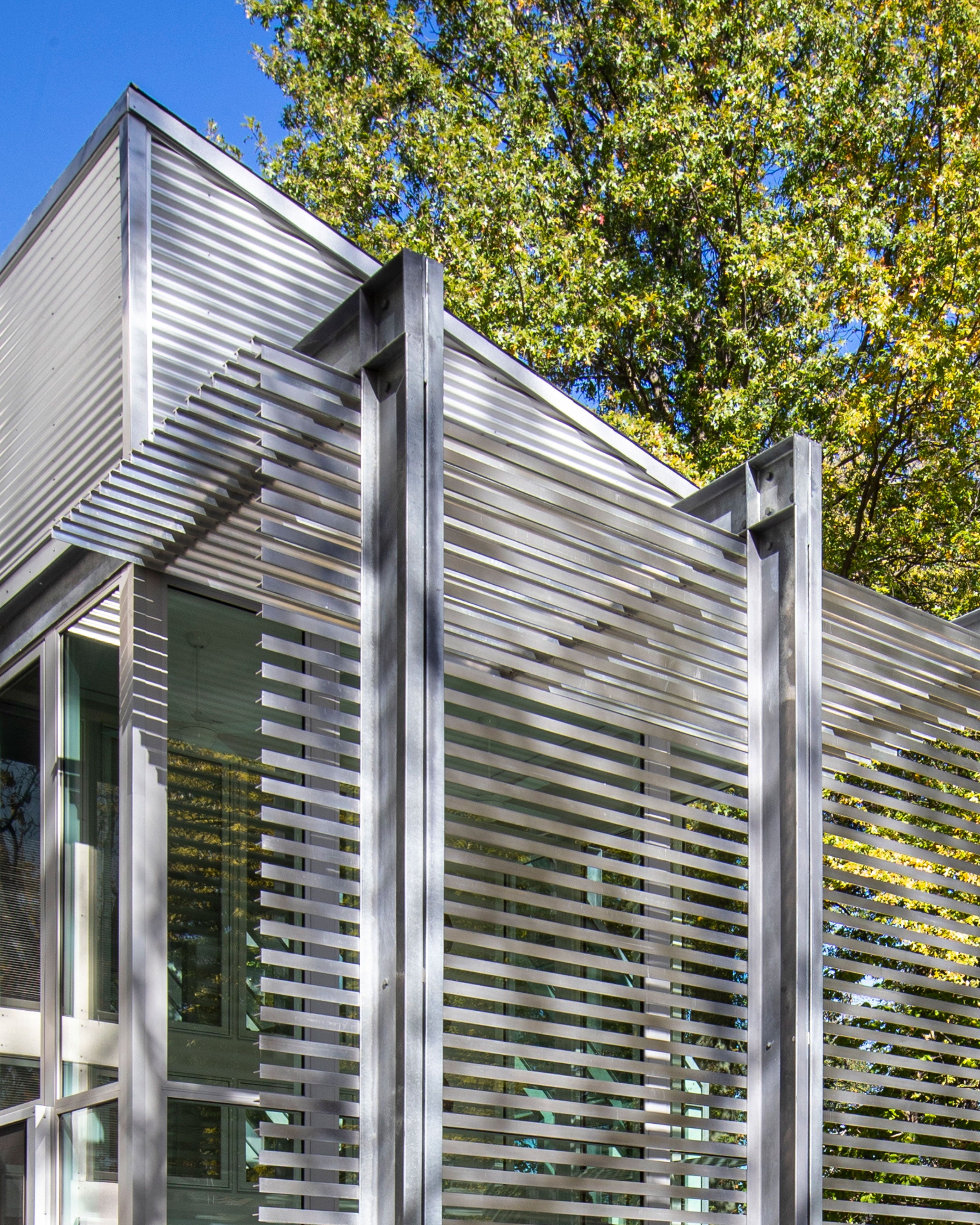 Modern Sunroom addition with exposed structural framing, Sun screen made up of standard metal sections. Akar Architecture.