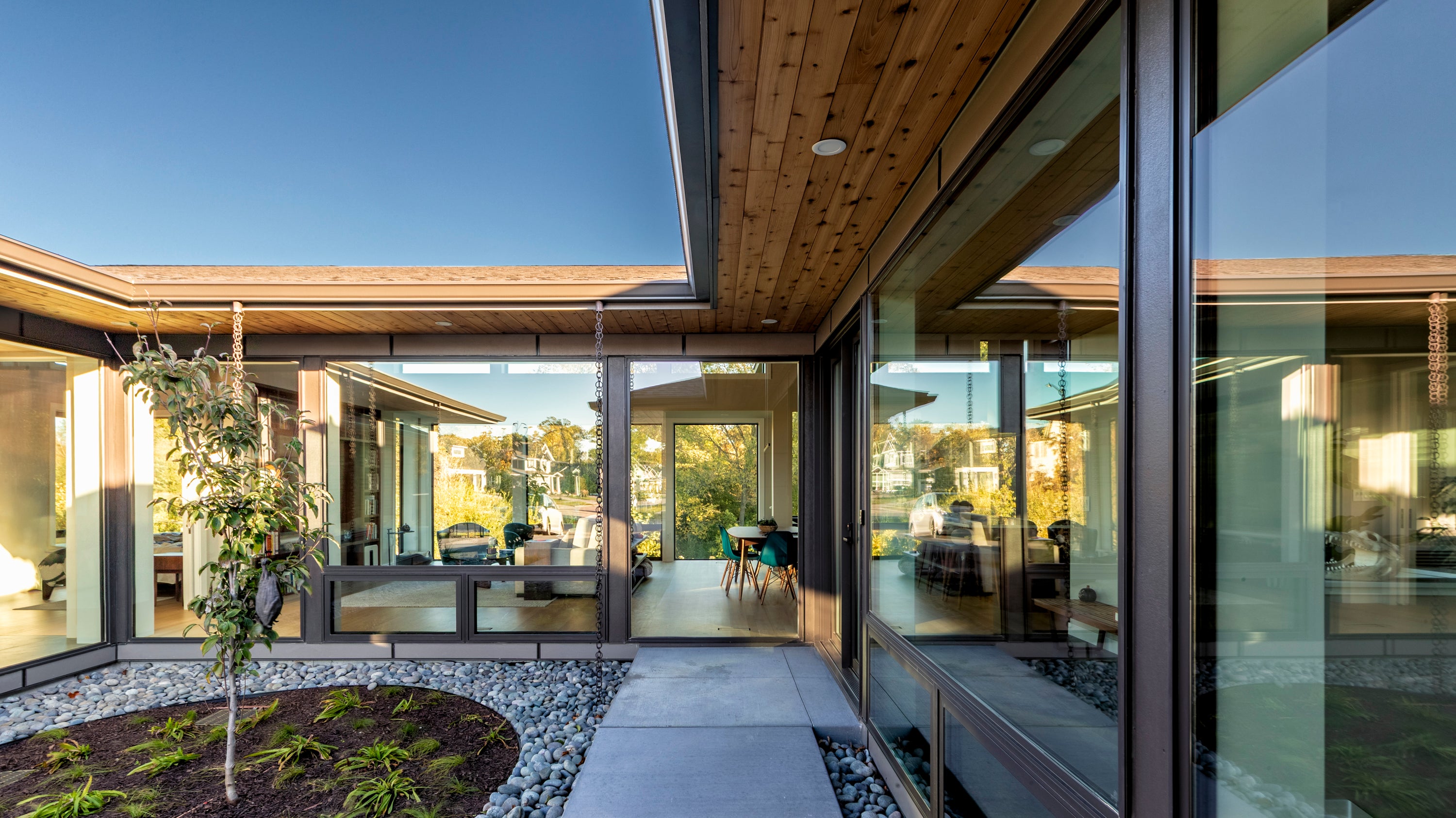Modern house interior with large glass windows and a courtyard area.