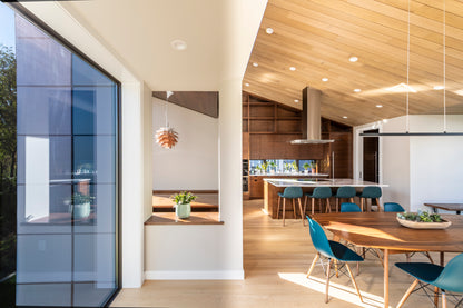 Modern kitchen and dining area with large glass door and wooden ceiling.