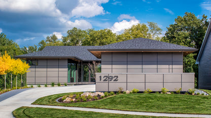 Modern Prairie style house with address number 1292, surrounded by trees and a clear sky.